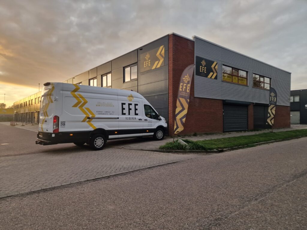 Bestelbus met belettering voor een bedrijfspand bij zonsondergang