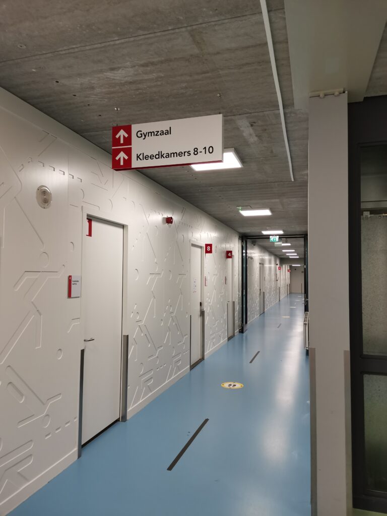 Hangend richtingbord in een gang van een sporthal