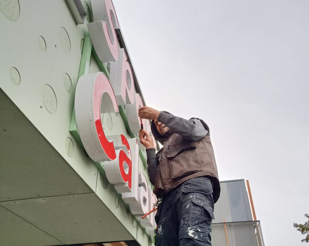 oppo_32 Monteur plaatst verlichte gevelletters op hoogte