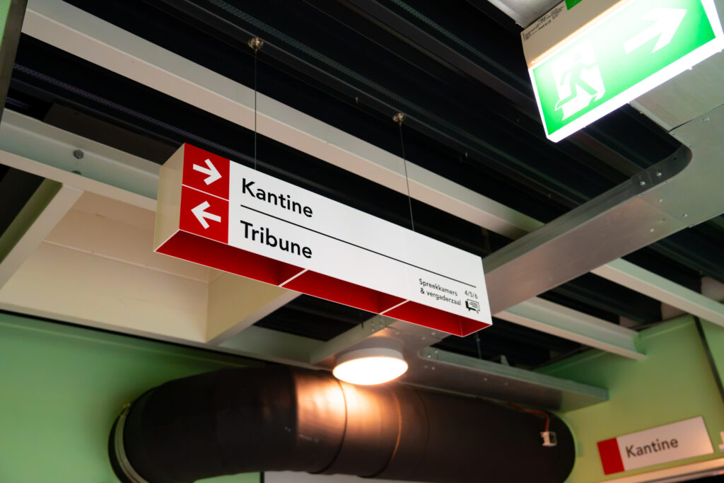 Hangende richtingborden naar kantine en tribune
